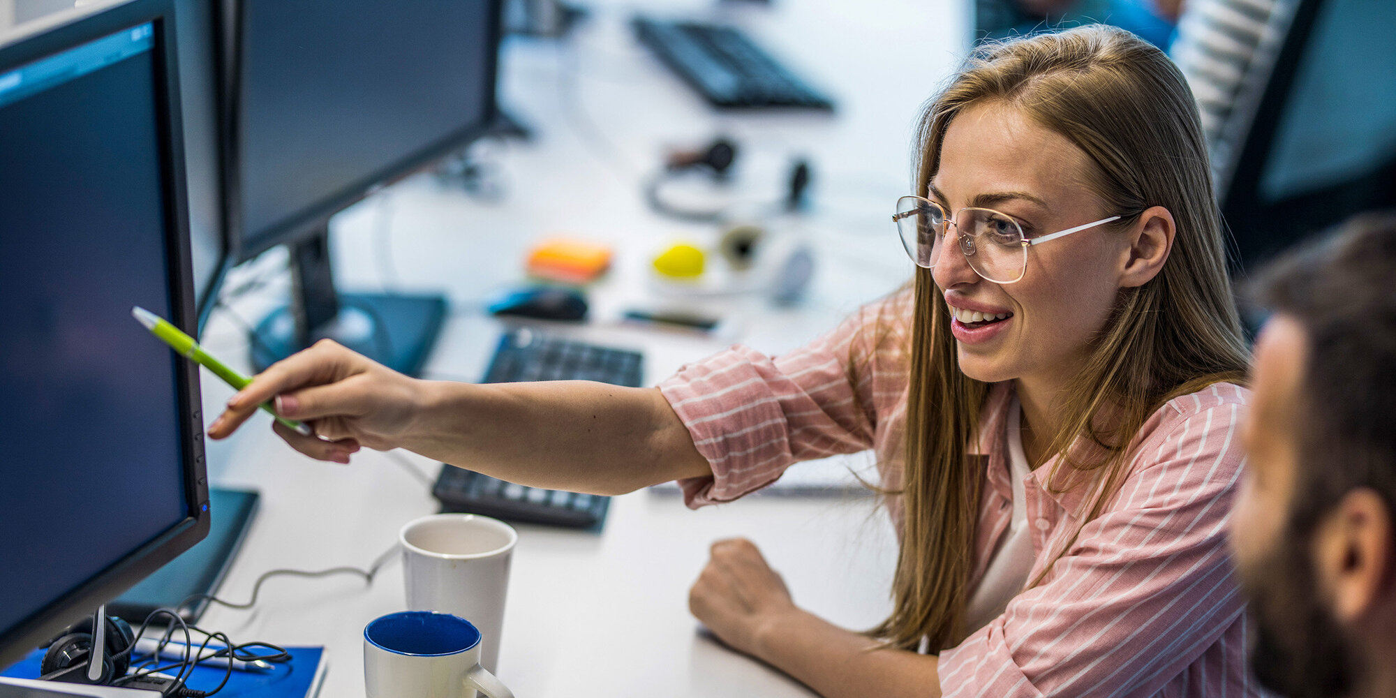 Junge Frau zeigt auf PC Monitor